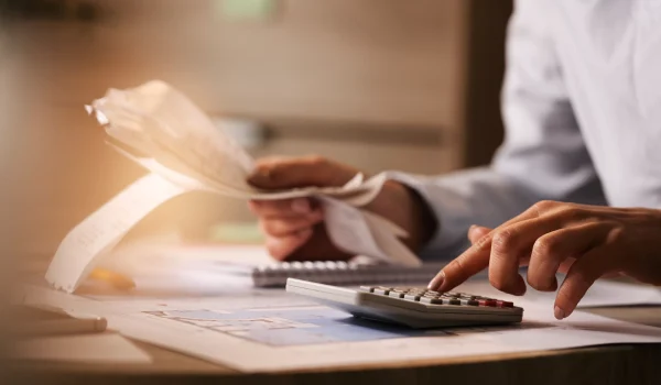 closeup-economist-using-calculator-while-going-through-bills-taxes-office